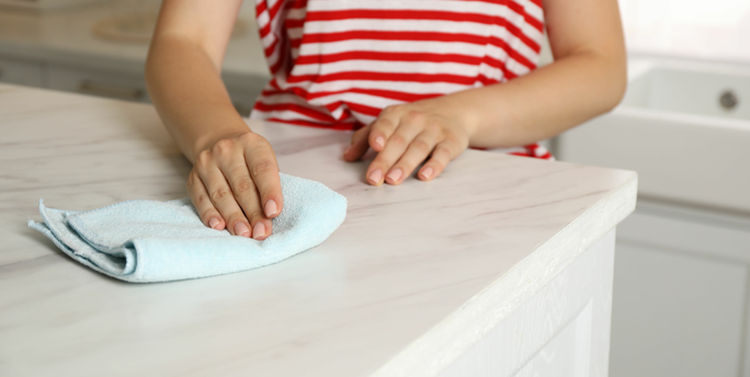 Ein Kunde reinigt stressfrei eine glänzende Natursteinoberfläche in seiner modernen Küche, die von SGM installiert wurde.