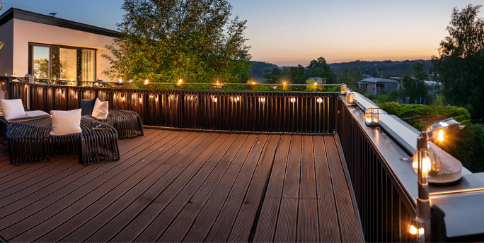 Gestaltungselemente wie Geländer und Beleuchtung fügen sich harmonisch in die Terrasse ein und schaffen eine einladende Atmosphäre.